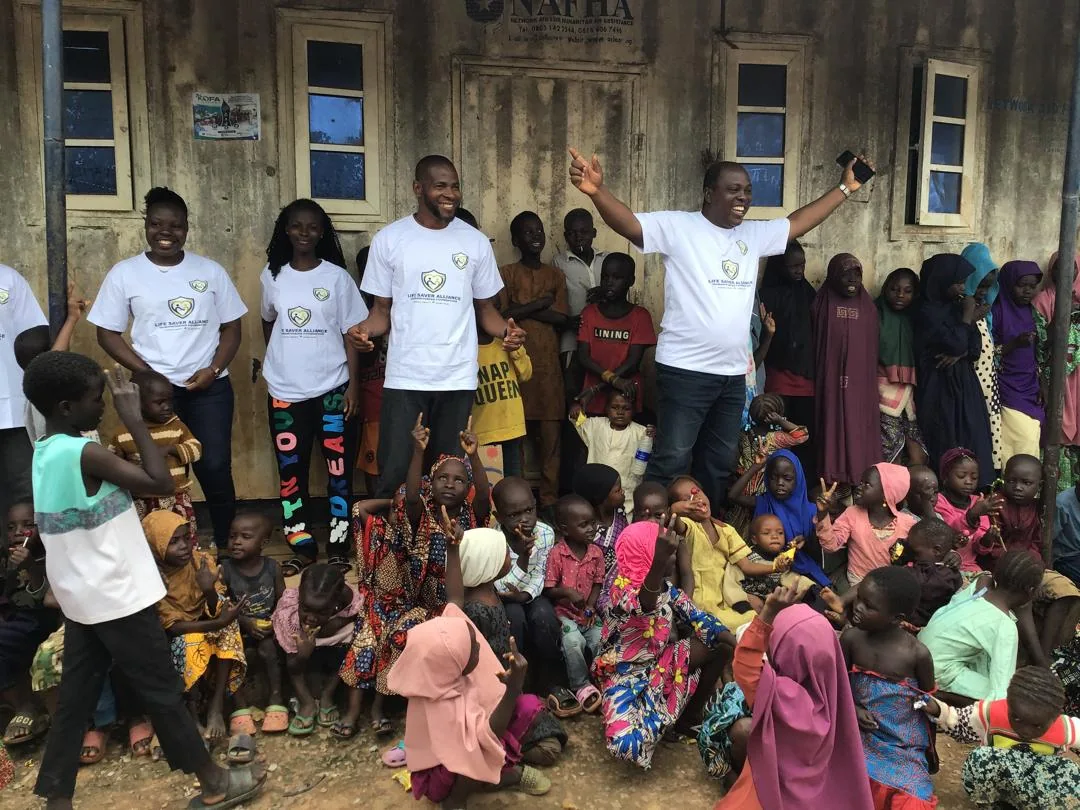 LAHF volunteers stand with children and families gathered at Durumi 1